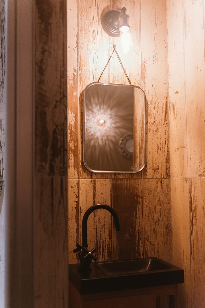 noesis-spa-des-lys-jungle-tropical-sanitaire Espace lavabo dans une salle de massage du spa, avec miroir et luminaire au design vintage